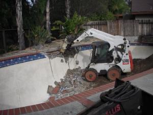 a professional tech is working with a small excavator on a Redwood City swimming pool removal job